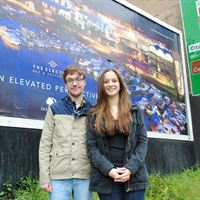 University of Lincoln students Sam Barber and Maria Sousa Machado infront of the billboard featuring the advert they designed for The Electric Bar and Restaurant 