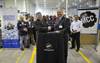 Textron Systems Canada General Manager Neil Rutter (left) and Mobile Climate Control President Bob Kuzminski shake hands after signing a letter of intent to work together on upcoming military projects as workers look on.
