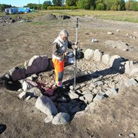 Arkeologen Lena Beronius mäter vid utgrävningar för E18 i Mälby. Fotograf: Peter Sillén