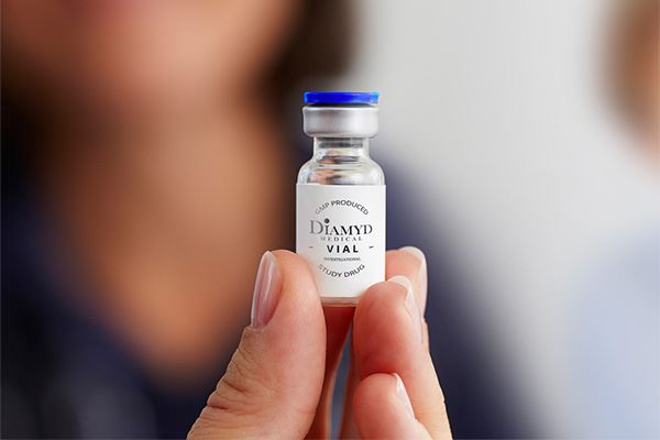 Kvinna som håller en liten flaska märkt "Diamyd Medical Vial Study Drug".