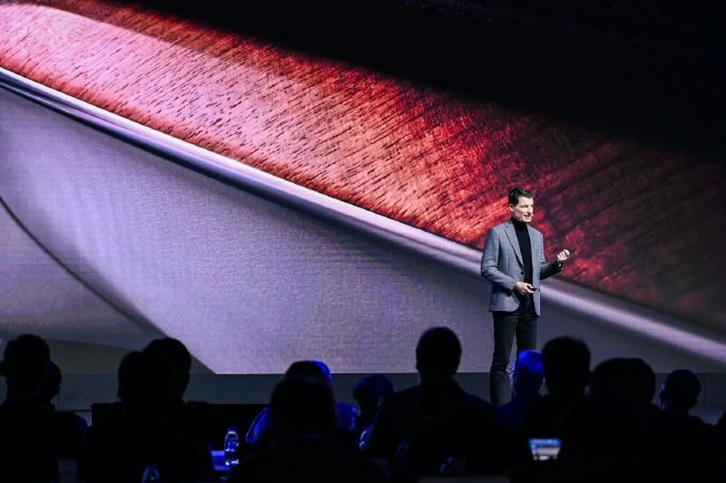 A person standing on a stage with a large screen
AI-generated content may be incorrect.