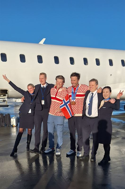 Norwegian athletes with crew of SAS airline, with the aircraft on the background.